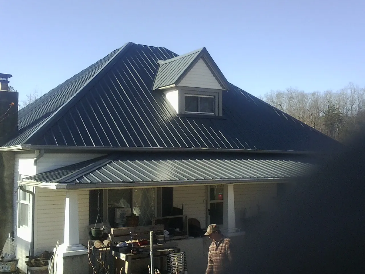 Dark blue standing seam metal roof with a dormer above a front porch in Jamestown